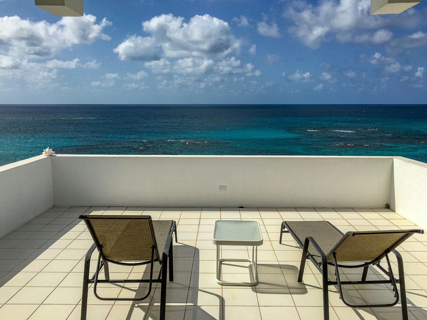 Terrazza esterna con sedie a sdraio affacciata su barriere coralline blu.