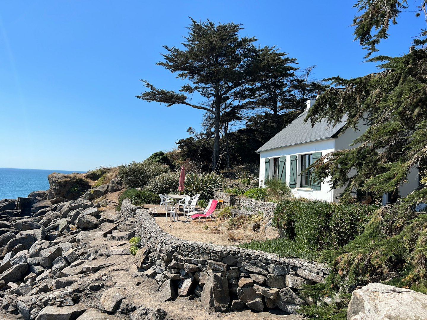 Casa bianca con persiane verdi affacciata sull'oceano.