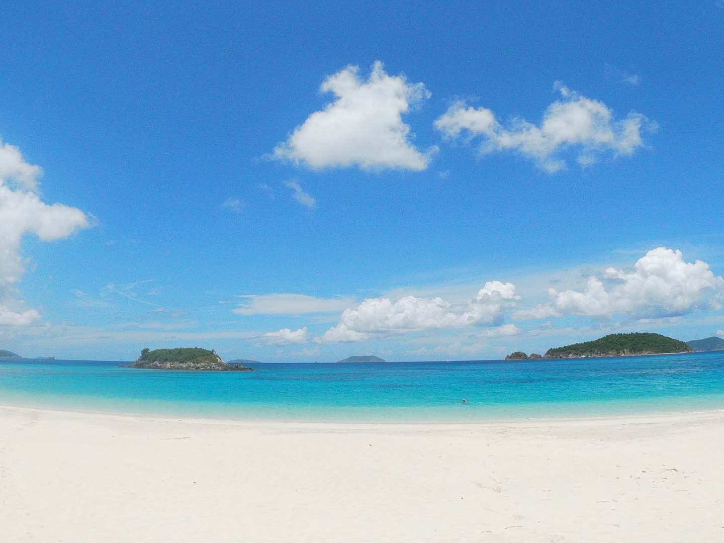 Isole tropicali si affacciano su acque turchesi dalla spiaggia sabbiosa.