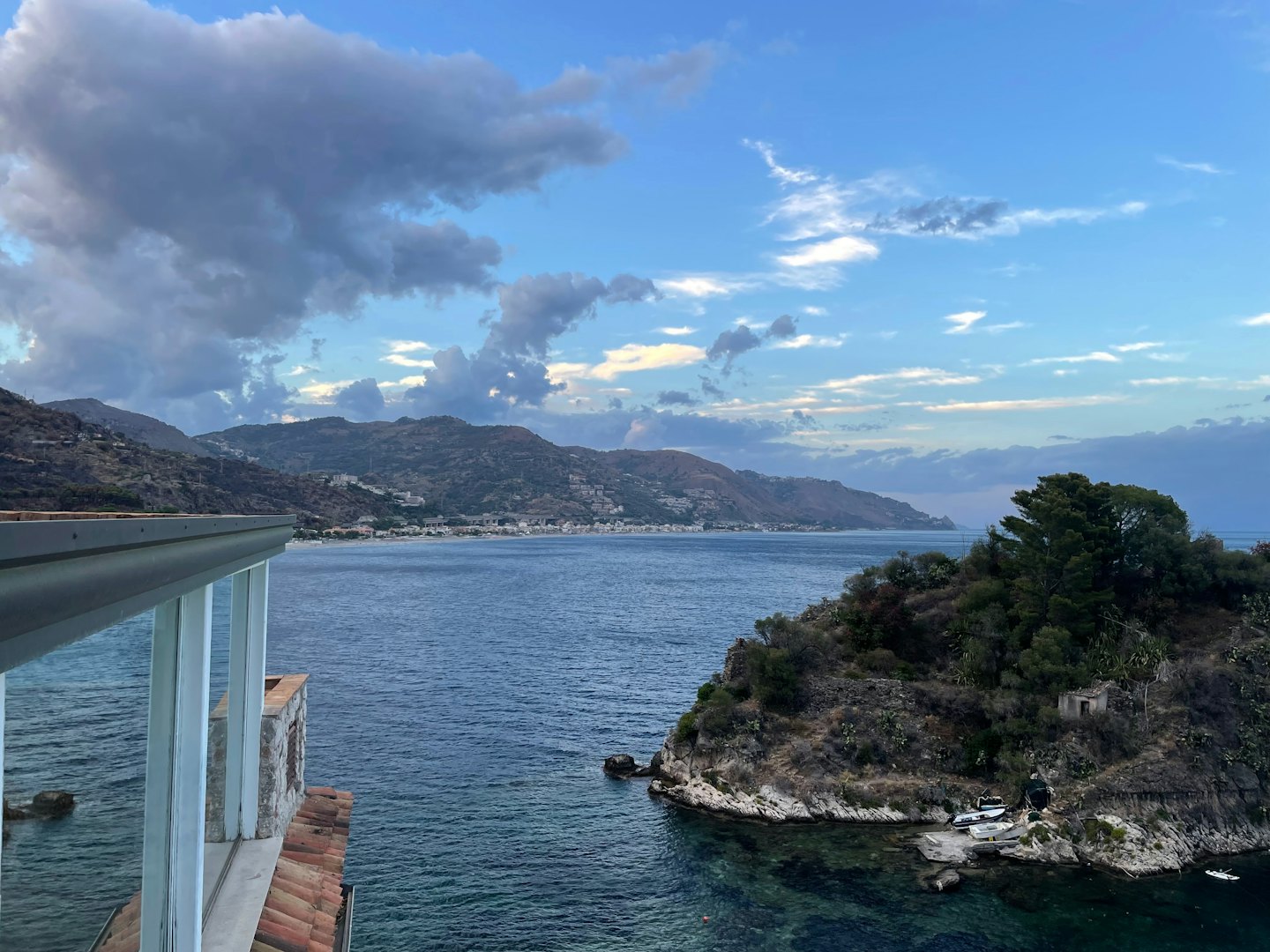 Vista di una baia panoramica con un'isola verde e montagne in lontananza.