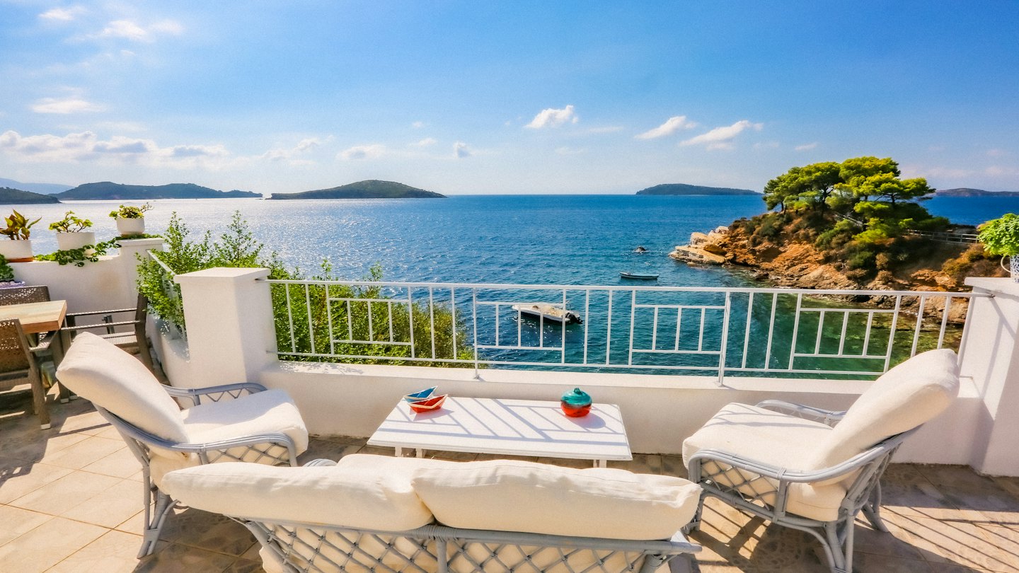 Mobili in vimini su un balcone con vista sul mare e sulle isole.