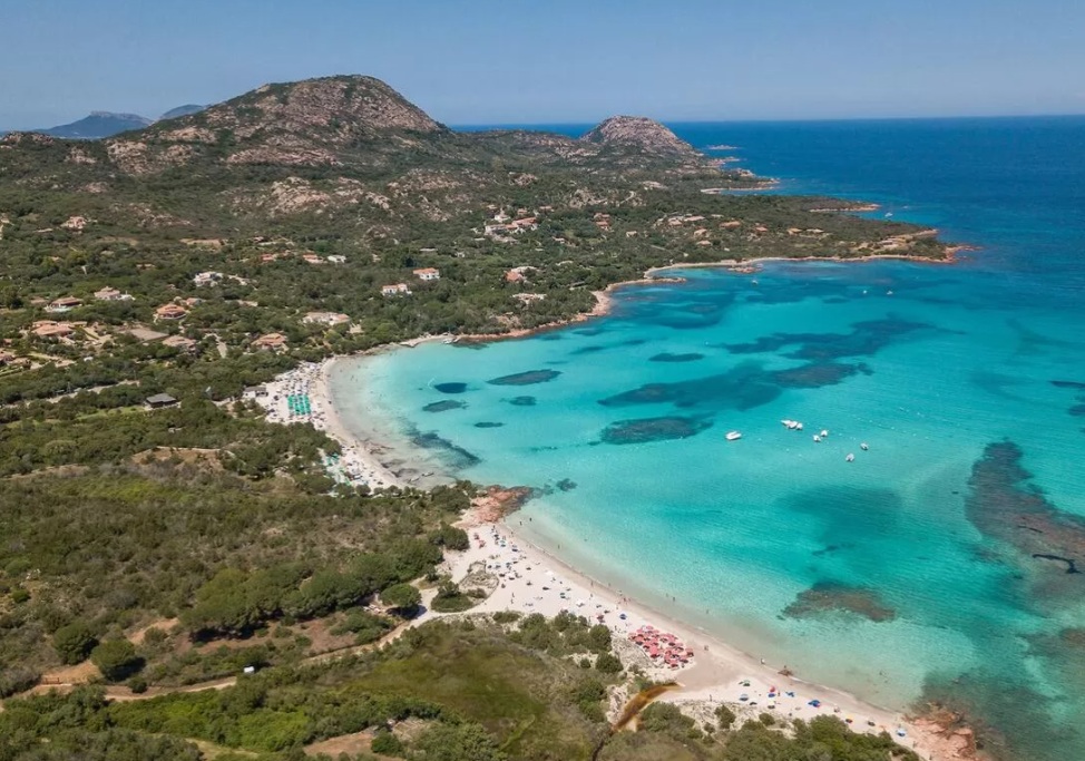 Edifici bianchi a gradoni con balconi si affacciano sul mare turchese.